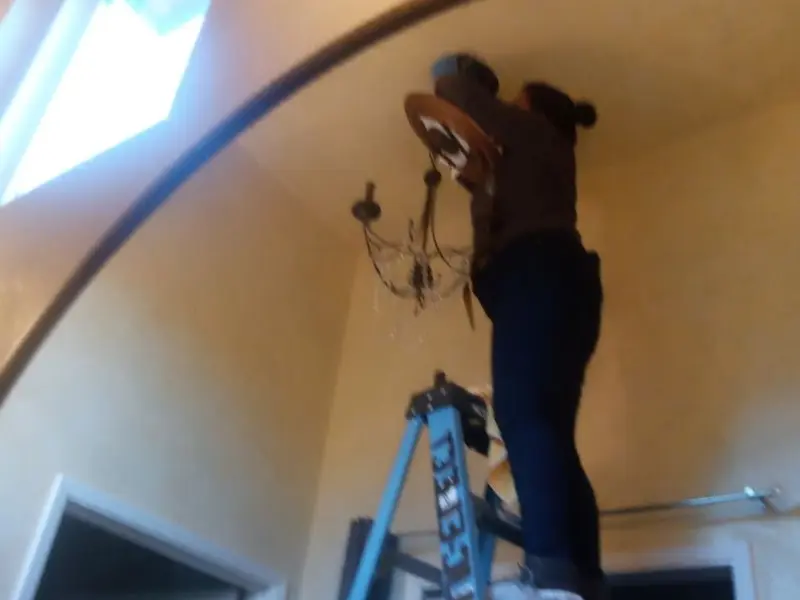 Electrician installing a chandelier in a Eveleth residence